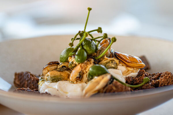 Gourmet mussels appetizer with capers, soft cheese, and crunchy bread at Naxaki Beach Lounge Restaurant in Naxos