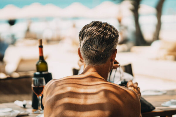 Guest at Naxaki Beach Lounge, sitting at a table and enjoying a meal with a glass of wine