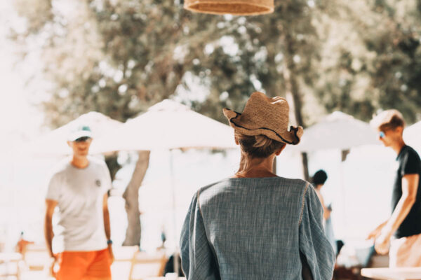 Guests interacting and enjoying their time at Naxaki Beach Lounge, with one guest wearing a stylish sunhat