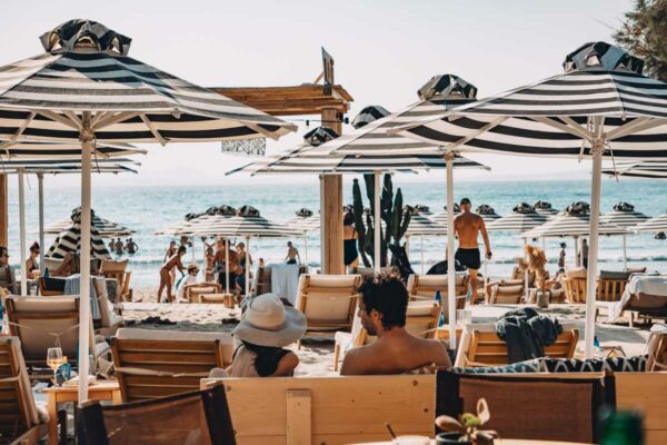 Guests relaxing on the sunbeds at the beach in front of Naxaki Beach Lounge Restaurant