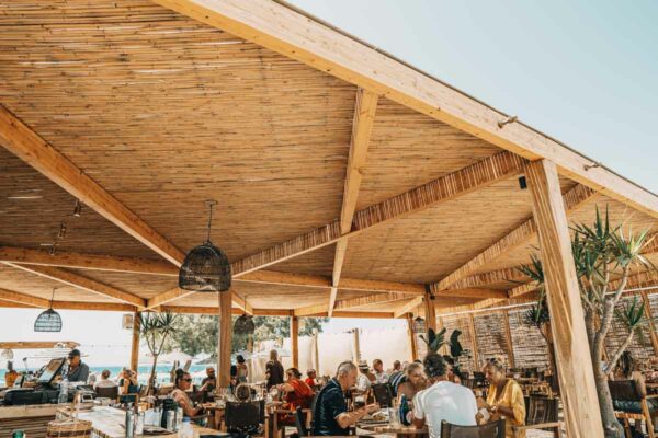 Guests dining under the wooden ceiling at Naxaki beach lounge restaurant