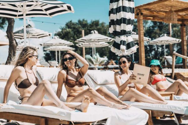 Group of friends relaxing on sun loungers at Naxaki Beach Lounge Restaurant.