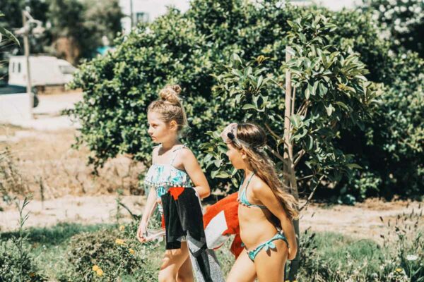 Two young girls in swimsuits walking with towels at Naxaki Beach Lounge Restaurant