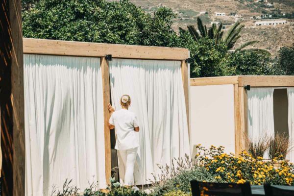 A therapist of naxaki beach lounge opening a curtain to a private massage cabana