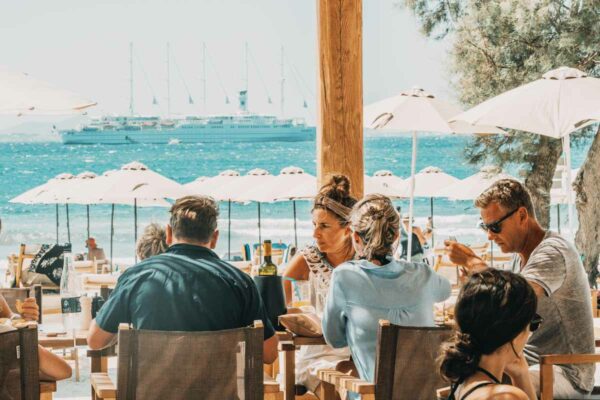 Guests dining with a view of the ocean and a cruise ship in the distance at Naxaki Beach Lounge Restaurant