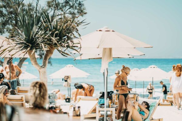 Guests relaxing under umbrellas at Naxaki Beach Lounge Restaurant with a beautiful ocean view