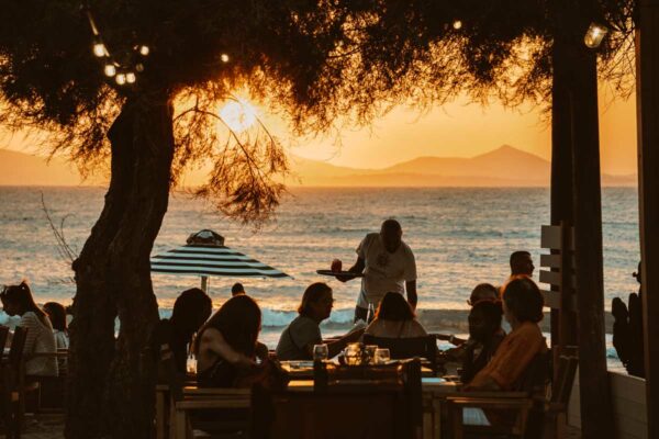 Guests dining at Naxaki Beach Lounge Restaurant during a picturesque sunset