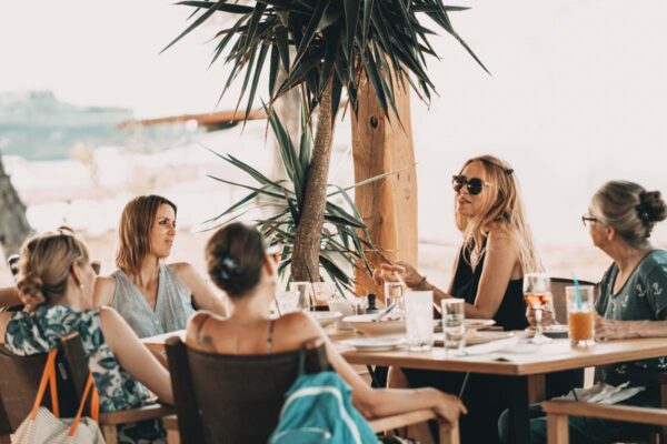 A group of women engaged in a lively conversation at Naxaki Beach Lounge Restaurant