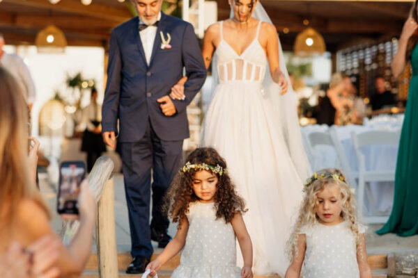 Bride and flower girls walking down the aisle at Naxaki Beach Lounge wedding