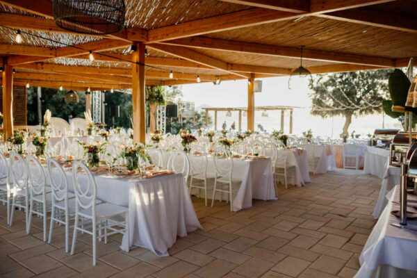 Spacious wedding dining area setup with white chairs and floral centerpieces at Naxaki Beach Lounge