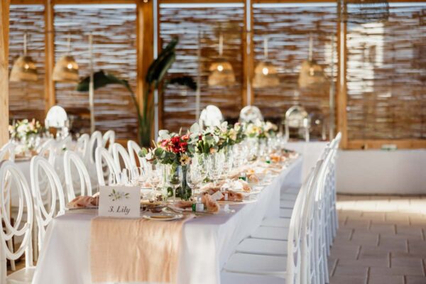 Beautifully decorated dining tables with flowers and place settings at Naxaki Beach Lounge wedding