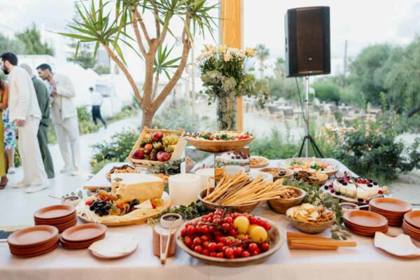 An assortment of food at a wedding buffet station, featuring fresh fruits, breadsticks, and cheese, set up at Naxaki Beach Lounge and Restaurant