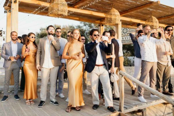 Wedding guests taking photos and enjoying the event at Naxaki Beach Lounge