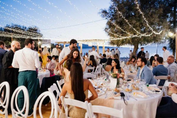 Wedding guests enjoying the reception under string lights at Naxaki Beach Lounge and Restaurant