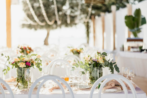 Reception tables adorned with floral arrangements at Naxaki Beach Lounge wedding event