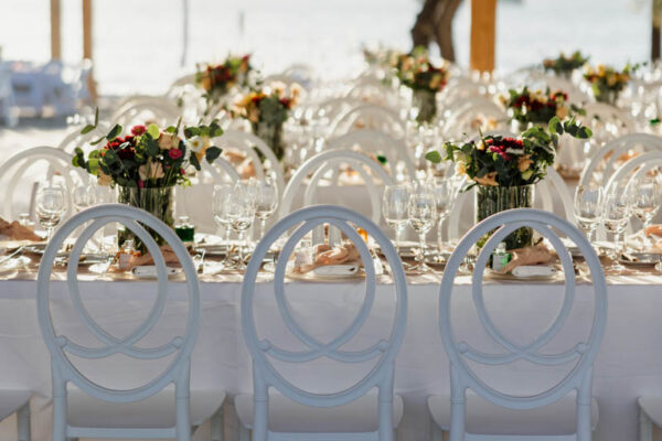 Wedding seating arrangement with white chairs and floral decor at Naxaki Beach Lounge