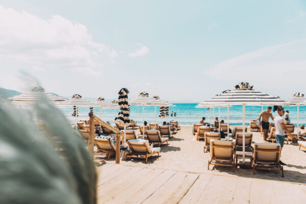 Guests enjoying sunbeds and umbrellas at the beachfront of Naxaki Lounge and Restaurant in Naxos, with a beautiful view of the sea