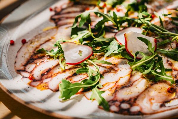 Delicious octopus carpaccio with fresh arugula and radish slices at Naxaki Beach Lounge Restaurant in Naxos