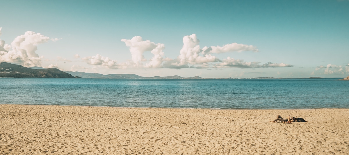 Agios Georgios Beach Naxos — wide golden sand beach with clear Aegean water and views across to Paros island on the horizon