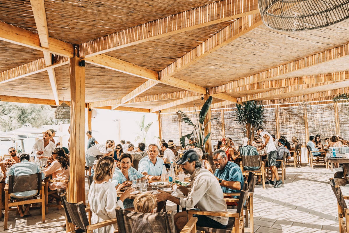 Naxaki Beach Bar and Restaurant on Agios Georgios Beach, Naxos — guests dining under bamboo canopy in a vibrant cosmopolitan beach atmosphere