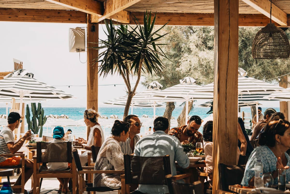 Naxaki Beach Lounge Bar and Restaurant on Agios Georgios Beach, Naxos — premium outdoor dining with striped umbrellas and turquoise Aegean sea views